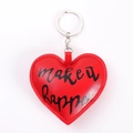Close-up of red heart leather keychain with silver ring and 'make it happen' text - Red Heart
