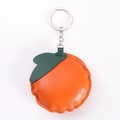 Detail of an orange fruit-shaped PU leather keychain with green leaf and silver ring - Orange