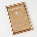 Detail view of rose gold passport holder featuring a lychee pattern and white logo - Gold