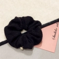 Macro shot of black knitted scrunchie texture with a polished gold heart pendant detail - Black