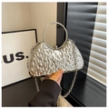 Detalle de bolso de noche plateado con textura de ondas y un asa metálica redonda - Plateado