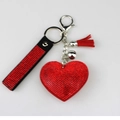 Detail van rode hartvormige hanger met kwastje en geweven koord op wit vlak - Rood