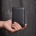 Close-up of black genuine leather wallet showing litchi grain texture and stitching - Black