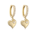 Detail of golden hoop earrings with sparkling heart pendant and cubic zirconia accents - Gold Padded Heart Earrings With White Zircon