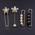 Détail d'un lot de 4 broches décoratives dorées avec strass et perles sur fond gris foncé - Ensemble N° 3