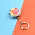 Close-up of a portable round metal pill box with floral pattern and keychain attachment - Rose Pattern (Round Pill Box + Keychain)