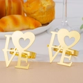 Close-up of golden LOVE napkin rings with heart detail on a rustic breakfast table - Gold Love