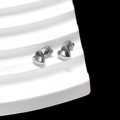 Detail of silver heart-shaped stud earrings on a white minimalist display stand - 3D Heart
