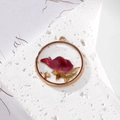 Détail d'un pendentif rond en résine avec une rose rouge séchée et des éclats d'or - Feuille d'Or Une Rose