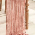 Wrinkled cheesecloth table runner in dusty rose hanging over a rustic wooden table edge - Flesh Pink