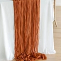 Burnt orange wrinkled cheesecloth table runner with soft texture on white cloth - Brown