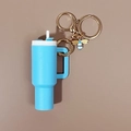 Dettaglio portachiavi mini tazza blu con chiusura dorata e ciondolo a forma di ape - Celeste