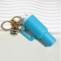Macro shot of blue mini tumbler keychain with golden ring and small Christmas tree charm - Christmas Blue