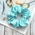 Elegant aqua blue satin scrunchie with silk texture on a lifestyle magazine background - Aqua