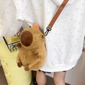 Adjustable brown Capybara plush crossbody bag worn by model in a cozy indoor setting - Small Brown / Small 25cm