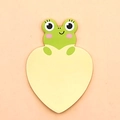 Cute green frog cartoon sticky notes with yellow heart-shaped writing area on pink background - Frog