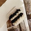 Close-up of four silk satin scrunchies in black and ivory cream on a nyunyu display card - Type D Black + White
