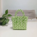 Close-up of green and white woven handbag with detailed textures on a white table - Mini Green Contrast