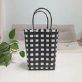 Detailed close-up of a black and white checkered woven tote bag with reinforced handles - Large / Black & White
