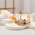 Detail eines Capybara-Schlüsselanhängers in transparentem Würfel mit goldenem Glitzer - Capybara-Apfel / Verlaufsgurt