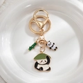 Close-up of golden metal panda keychain with green bamboo and enamel charms detail - Panda with Hat