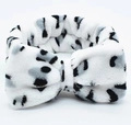 Close-up of soft coral fleece headband with black and white spotted leopard pattern - White Leopard