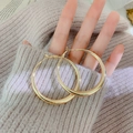 Orecchini rotondi geometrici minimalisti in oro lucido tenuti in mano - Cerchio Oro Lucido con Perno in Argento