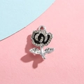 Colgante de rosa plateada con esmalte negro y pedrería blanca sobre fondo de color - Rosa Negra Plata