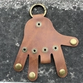 Dettaglio del portachiavi a forma di mano in pelle marrone con bottoni in ottone - Pelle PU marrone