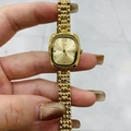 Detail of gold rectangular watch dial with woven chain strap and Roman numeral XII - Gold Case Gold Dial