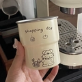 Camping mug with cartoon dog print and Shopping Day text held in hand by coffee machine - Shopping Dog