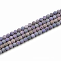 Macro shot of 10mm round purple natural stone beads with unique speckled patterns - Violet