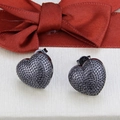 Primer plano de pendientes de corazón negros con textura perlada sobre un fondo de cinta roja - Stud aretes / Negro