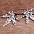 Detailed top view of retro silver alloy maple leaf pendants on a natural wood surface - 38x39mm / Large Antique Silver