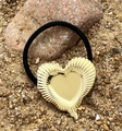 Dettaglio di un elastico nero per capelli con grande ciondolo a cuore dorato su pietra - Cuore d'oro