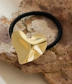 Detailed close-up of a gold textured heart-shaped metal charm on a black elastic hair tie - 3D Heart Shape