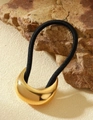 Detail einer halbmondförmigen goldenen Haarspange mit schwarzem Haargummi auf einem Stein - Mondsichel Gold
