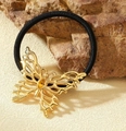 Makro-Detail von goldenem Schmetterlings-Haargummi auf natürlichem Felsenhintergrund - Schmetterling Gold