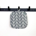 Thick square grey cotton trivet with geometric pattern hanging on a metal hook - Grey Arrow