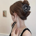 Detailed view of an elegant black satin camellia flower scrunchie on a ponytail - Hair Claw / Black