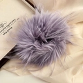 Close-up of a soft purple faux fur hair tie resting on elegant silk fabric background - Purple
