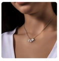 Dettaglio di una collana con pendente LIAM in argento indossata da una modella in luce soffusa - Lettera A / Argento