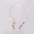 Close-up of white microfiber tubular shoulder strap with gold lobster clasps and knots - White