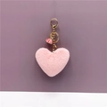 Dettaglio del portachiavi a cuore in peluche rosa con chiusura dorata e nappa - Rosa