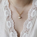 Détail d'un collier cœur plaqué or 18 carats avec nacre blanche et chaîne trombone - Collier