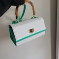Détail de la poignée en bambou et du fermoir sur un sac à main motif crocodile - Vert