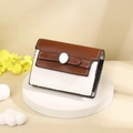 Detail of a brown and white leather card wallet with a silver metal clasp on a display stand - White