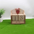 Calendrier perpétuel en bois avec cœur rouge et ruban posé sur gazon vert - Cœur Rouge Rétro