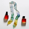 Detail view of van Gogh style wheat field oil painting silk scarf with elegant perfume bottles - Sunset