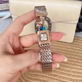 Close-up of a luxury rose gold rectangular padlock watch held against a beige handbag - Rose Gold
